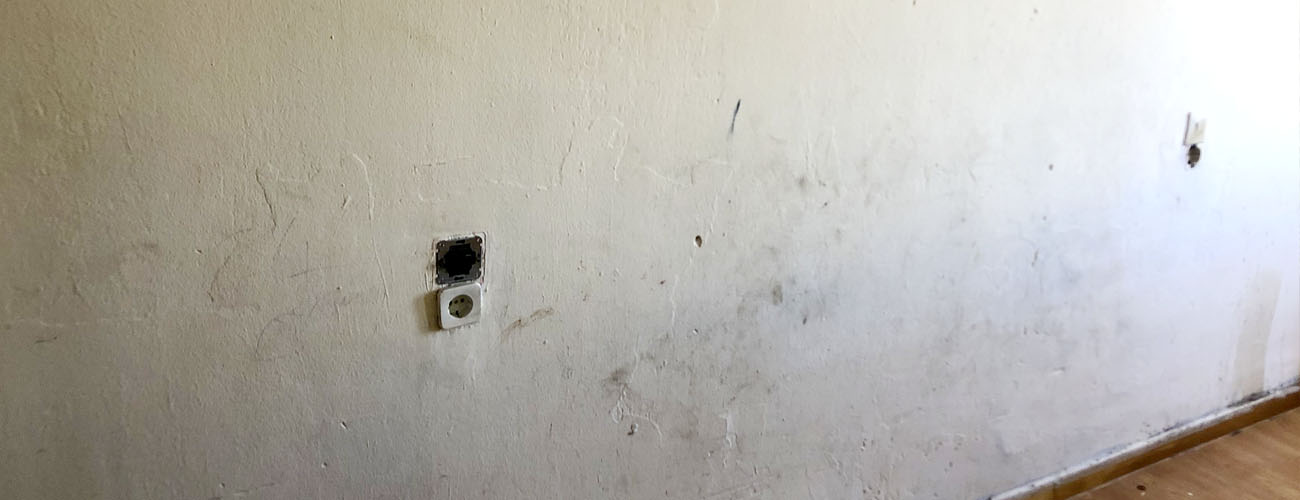 El maestro está aplicando masilla blanca en una pared y manchando con una  espátula en una sala de renovación de la casa durante el día